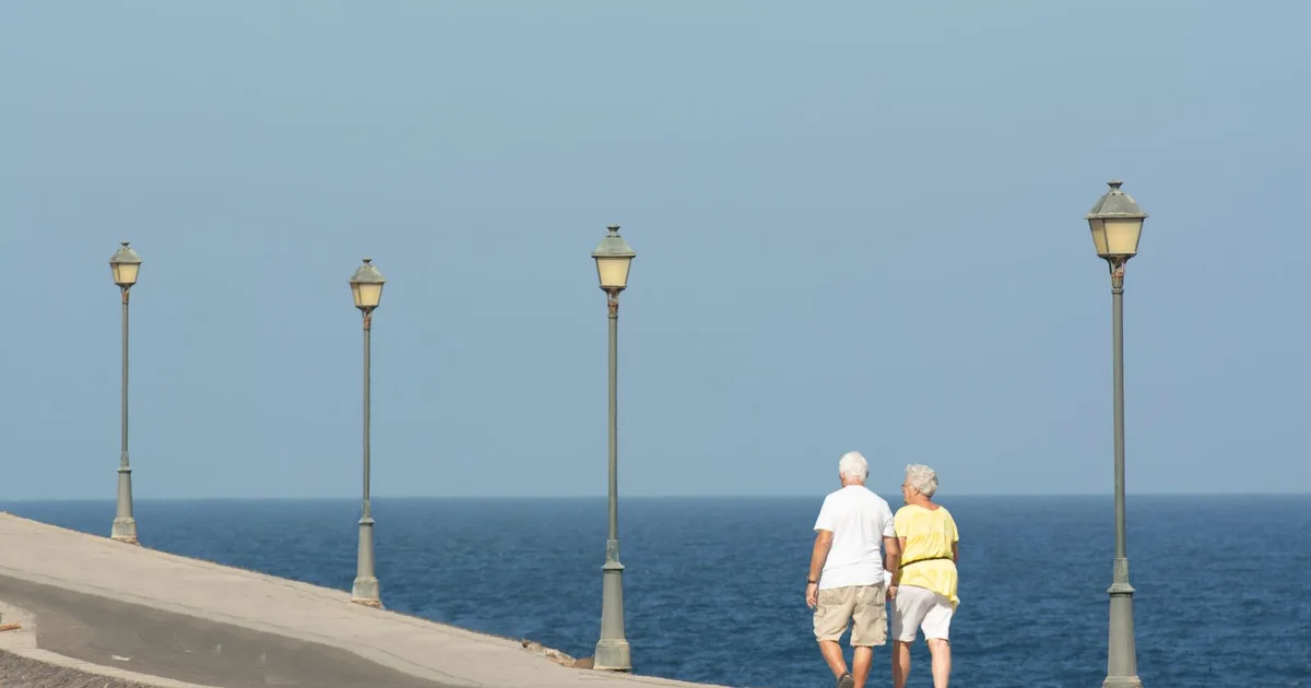Older couple walking together on a seaside promenade on a sunny day